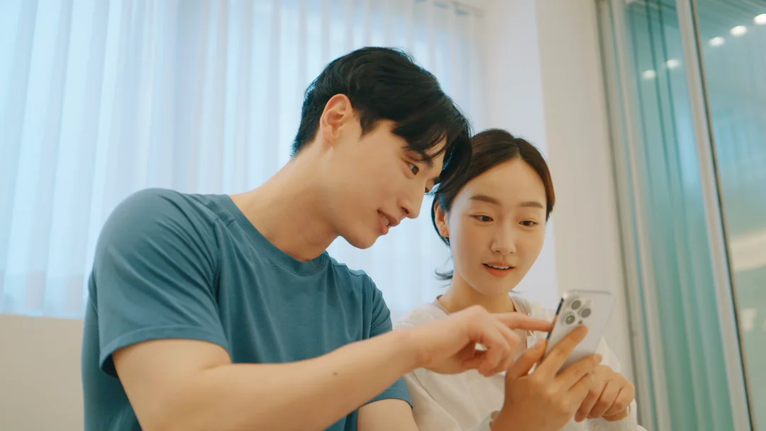 휴대폰 화면을 손으로 짚으며 이야기하는 회원과 강사
